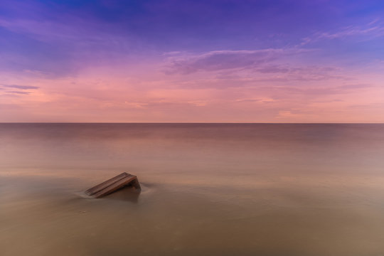Fototapeta abstract single wood box sink in sand and sea surreal twilight