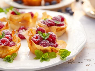Foto auf Leinwand Phyllo cups with Mascarpone cheese filling topped with fresh Raspberries and mint on a white plate © zi3000