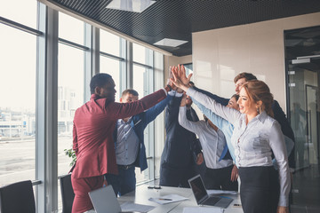Happy successful multiracial business team giving a high fives gesture as they laugh and cheer...