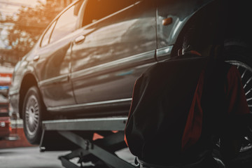 Professional car mechanic changing wheel in auto repair service. worker repairs detail in garage