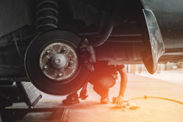 Car mechanic Repairing brakes pads on car in garage