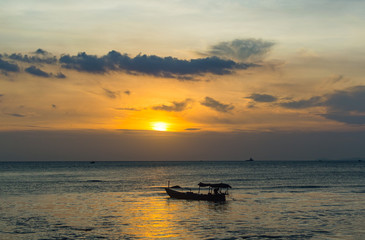 Fototapeta na wymiar Silhouette of fishing boat on the beach in golden sunset