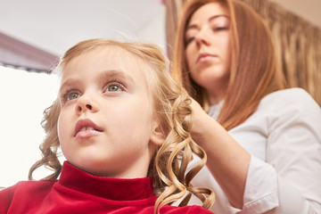 Kid at hairdresser close up. Face of little blonde girl.
