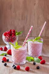 Tasty blueberry, strawberry, raspberry and yogurt smoothies with berries and mint around on wooden background