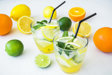 citrus lemonade with limes, mint and lemons in glasses on white table