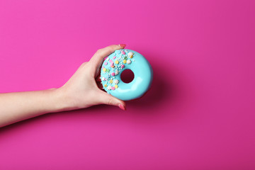 Female hand holding sweet donut with sprinkles - Powered by Adobe