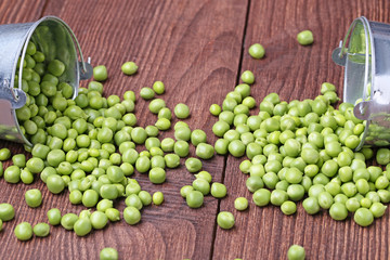 Fresh green peas in bucket on brown wooden table