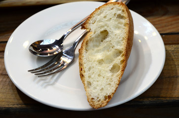 A slice of bread with spoon and fork on white plate