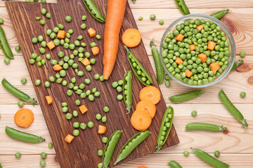 Green peas and carrots sliced on wooden table