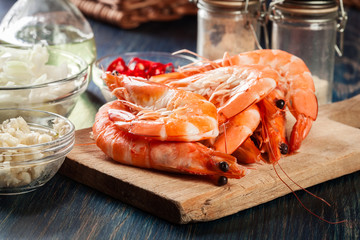 Selection of shrimp ready for frying with onion, garlic, chili and lime on cutting board