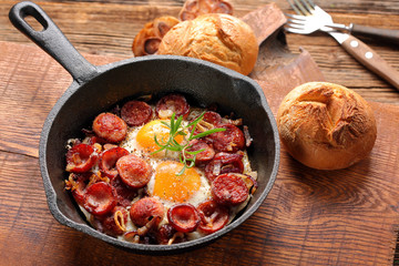 Fried eggs with sausage and onion on frying pan