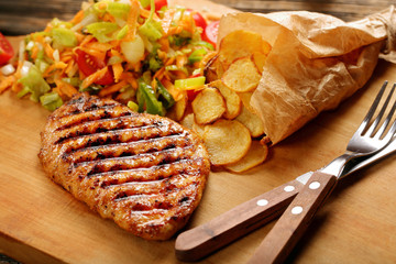 Grilled chicken breast fillet with potato chips and salad