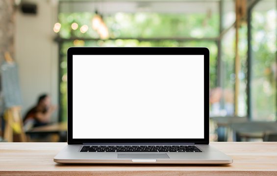 Laptop with blank screen on wood table and coffee shop background. Clipping path include.