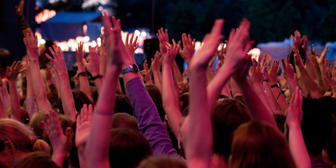 At the concert the crowd supports the musicians by raising their hands