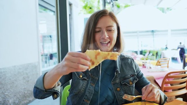 Young woman eating pizza in the restaurant, outdoors