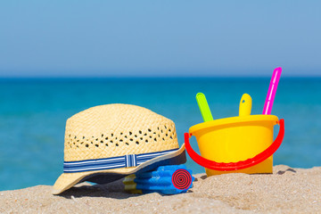 Plastic bucket, water pump and straw hat on the sea background on the beach.