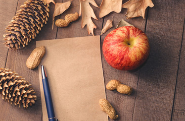 Frame of autumn leaves about page from notebook and pen with red apple