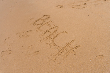 Beach word on sand on the the beach as background. Summer time