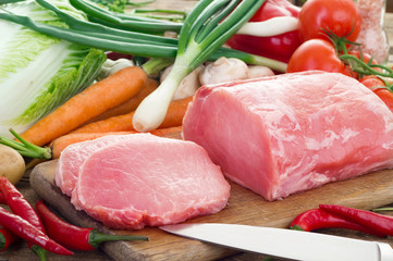 Fresh meat and vegetables on kitchen board