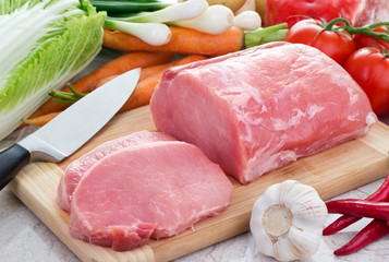 Fresh meat and vegetables on kitchen board