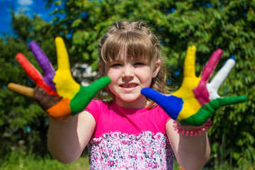 Cute girl showing her hands painted in bright colors. Art and painitng concept