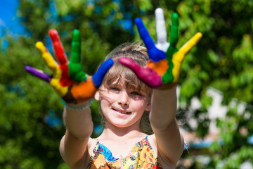 Cute girl showing her hands painted in bright colors. Art and painitng concept