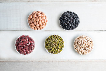 Mixed beans in bowl on wood background.