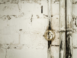 Alter zersprungener Lichtschalter und Rohre auf Mauerwerk