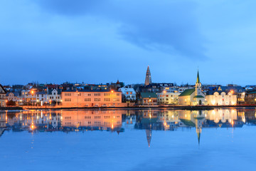 Fototapeta na wymiar Beautiful reflection of the cityscape of Reykjavik in lake Tjornin at the blue hour in winter