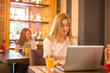 Teenage girl working at her laptop in cafe.