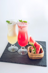 Fresh smoothie in glass with sliced pieces of watermelon and melon with mint on white isolated background. Summer drinks