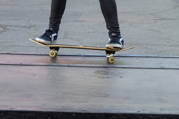 Plakat Skateboarder legs riding skateboard at skatepark
