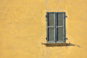 Closed green windows on yellow wall of old house in Florence city, Italy