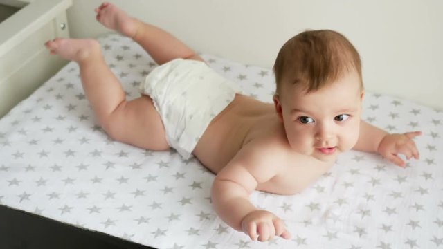 baby boy in diaper lying on her belly on the diaper with the stars next to a white wall on the table of the house
