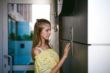 woman dials an apartment code on an electronic doorphone panel