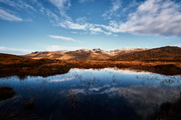 Berge bedeckt mit Schnee im Winter in Donegal Irland mit See im Vordergrund und einem bewölkten Himmel