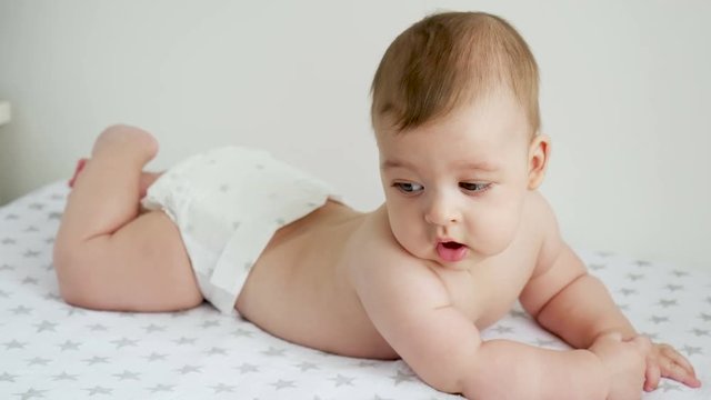 baby boy in diaper lying on her belly on the diaper with the stars next to a white wall on the table of the house