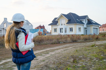 beatiful woman engineer is standing serious in front of a building site