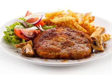 Fried pork chop, French fries and vegetable salad on white background