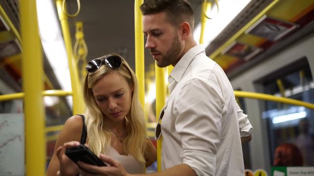 4K travel video young sightseeing couple in subway looking at map on mobile phone
