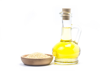 Sesame seeds and bottle with oil on a old wooden table?Sesame oil oil in a glass jug.