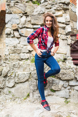 Pretty young slim woman posing against stone wall
