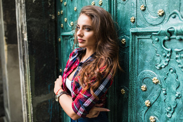 portrait of cute smiling woman on a background of green vintage door wearing casual clothes in summer city