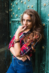 Fototapeta premium portrait of cute smiling woman on a background of green vintage door wearing casual clothes in summer city