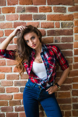 Young pretty hipster girl posing on brick wall