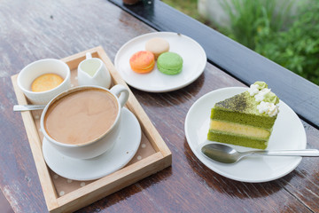 hot coffee breakfast set with green tea cake and fresh .macaroon in cozy outdoor cafe