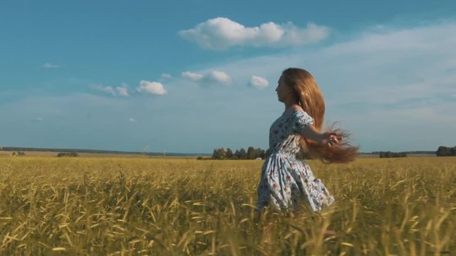 Pretty girl running through yellow wheat field. Happy beautiful young woman outdoors enjoying nature. Free, Freedom concept. Golden Wheat.