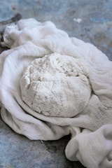 Fresh cooking homemade cottage cheese in gauze textile over gray metal background. Rustic style, day light