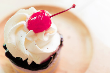 Cupcake with whipped cream and cherry from top view