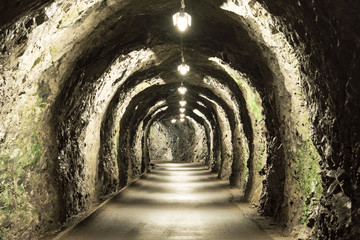 old basic tunnel through a mountain in the Swiss Alps with sparse lighting
